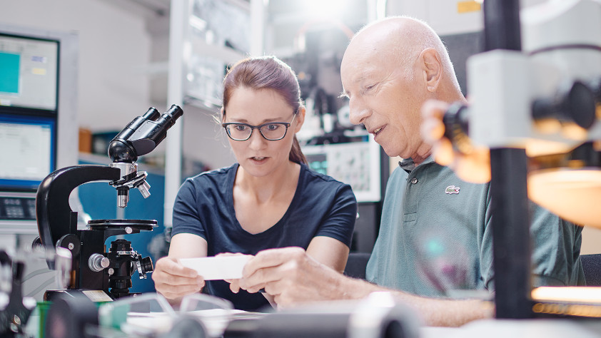 Young woman and older man looking at technical things